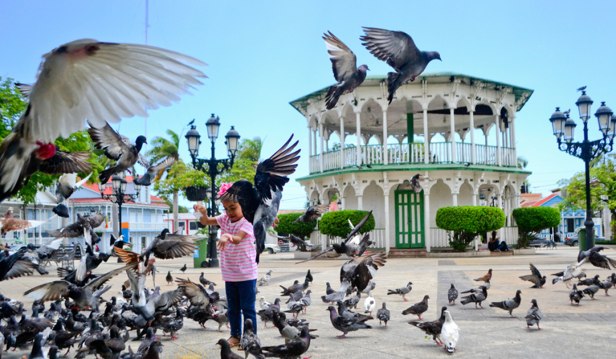 View of a girl feeding doves at the Central Park of Dominican Republic - Marysol Tours - Puerto Plata City Tour