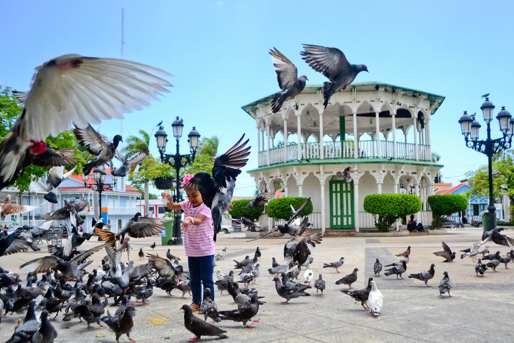 View of a girl feeding doves at the Central Park of Dominican Republic